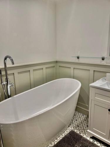 a white bath tub in a bathroom with a sink at Flat 8- Garden Square in Banbury