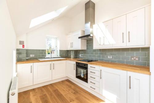 a kitchen with white cabinets and a sink and a stove at Flat 9- Park Place in Banbury