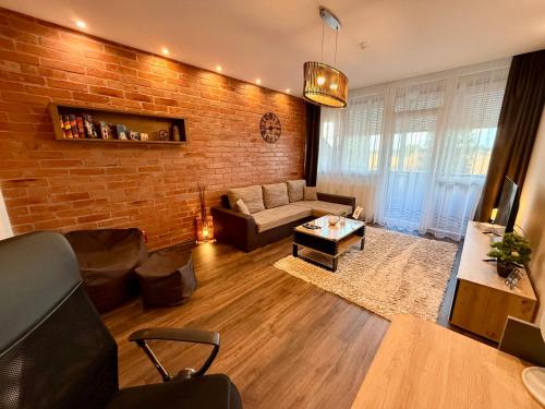 a living room with a couch and a brick wall at City Edge Hideaway Apartment in Nagykanizsa