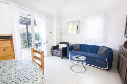 a living room with a blue couch and a chair at LES MARINES 2 - Villa en résidence avec piscine à 2 pas de la plage - Clim - parking in Saint-Cyprien