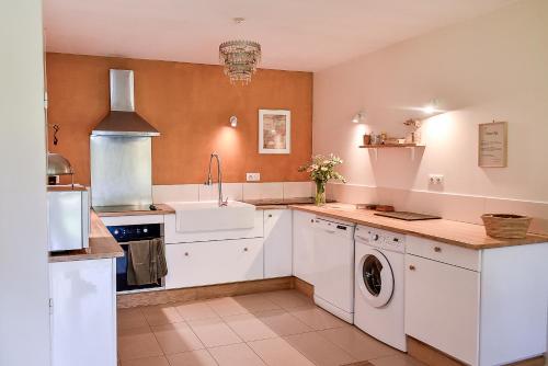 a kitchen with white cabinets and a sink at Maison Chalendeix in Nedde