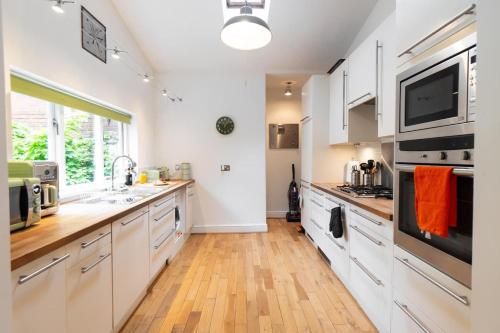 a kitchen with white cabinets and a wooden floor at Spacious Victorian for 10 across Royal Infirmary in Leicester