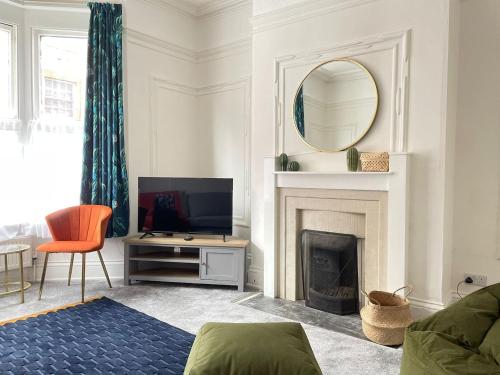 a living room with a television and a fireplace at Spacious Victorian for 10 across Royal Infirmary in Leicester