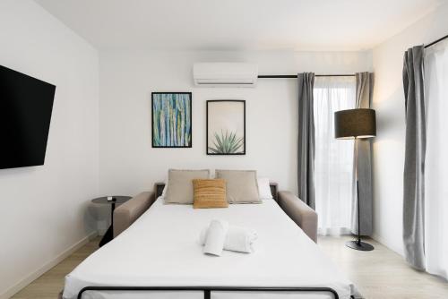a white bedroom with a bed and a window at MÁ HOMES Postigos in Málaga