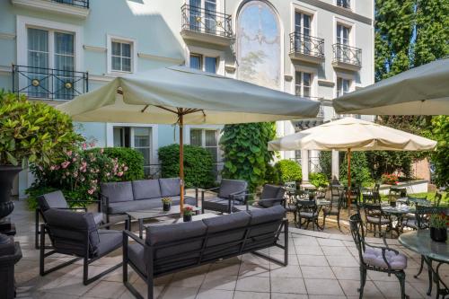 an outdoor patio with tables and chairs and umbrellas at Potsdam Hotel Am Jägertor in Potsdam