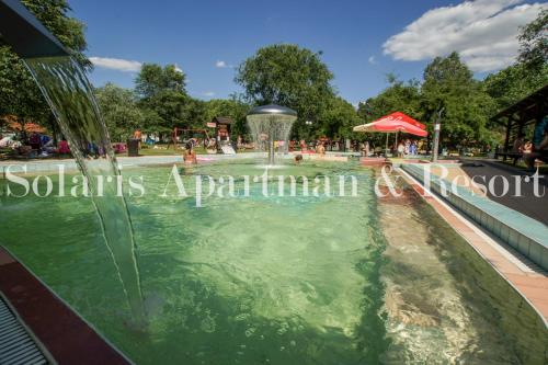 a fountain in a swimming pool in a park at Solaris Apartman&Resort in Cserkeszőlő