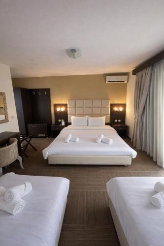 ein Hotelzimmer mit zwei Betten mit weißer Bettwäsche in der Unterkunft Thelxis in Volos