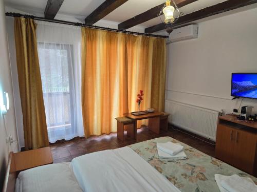 a bedroom with two beds and a table and a television at Casa Vivian in Băile Herculane