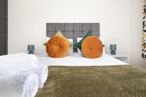 a bedroom with a white bed with orange pillows at Unique 2Bedroom Flats in Bicester in Bicester