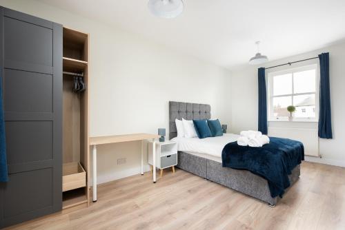 a bedroom with a bed and a desk and a window at Unique 2Bedroom Flats in Bicester in Bicester