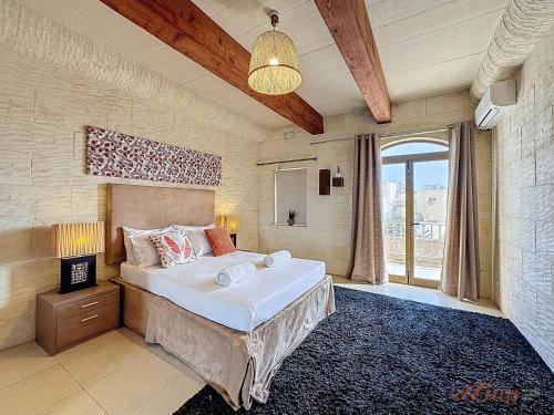 a bedroom with a large bed and a large window at Mia - Your Gozo Haven with Pool in Xagħra