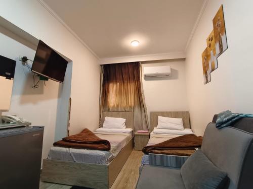 a small room with two beds and a tv at فندق أجياد Agyad Hotel in Asyut