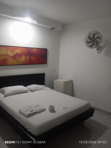 ein Schlafzimmer mit einem weißen Bett und einem Gemälde an der Wand in der Unterkunft Hotel eden centro in Medellín