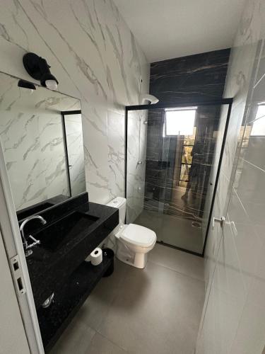 a bathroom with a sink and a toilet and a shower at Casa geminada a 250 metros do mar in Imbituba