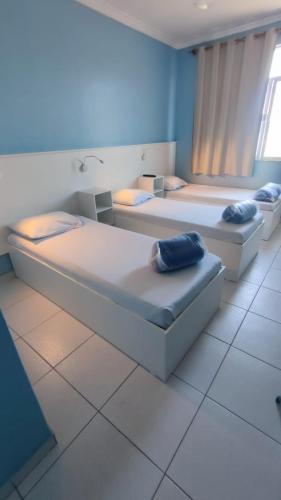 two beds in a room with blue walls at Hotel Portugal in Macaé
