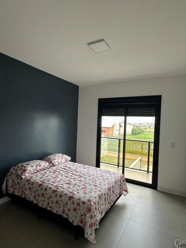 a bedroom with a bed and a large window at Casa geminada a 250 metros do mar in Imbituba