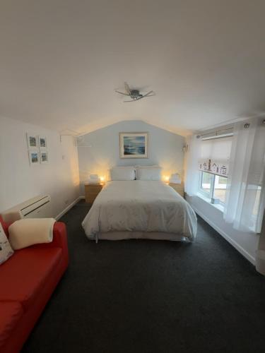 a bedroom with a bed and a red couch at The Garden Suite Holt in Holt