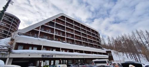 a building covered in snow with cars parked in front of it at Cervino loft in Breuil-Cervinia