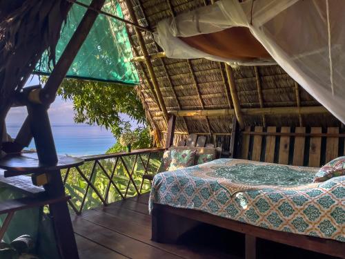 a bed in a thatched room with a view of the ocean at Finca Exótica in Carate