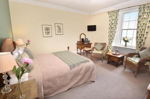 a bedroom with a bed and a chair and a television at The Royal Hotel Cromarty in Cromarty