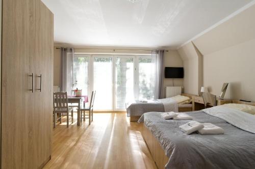 a bedroom with two beds and a dining room with a table at LC pokoje & apartamenty in Pobierowo