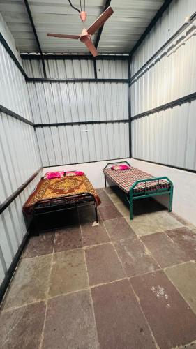 a room with two beds and a ceiling fan at Sumai Bhakt Niwas in Tuljapur