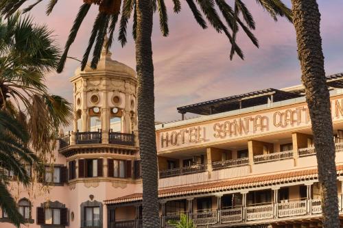 a hotel with a clock tower and palm trees at Santa Catalina, a Royal Hideaway Hotel - Gran Lujo in Las Palmas de Gran Canaria
