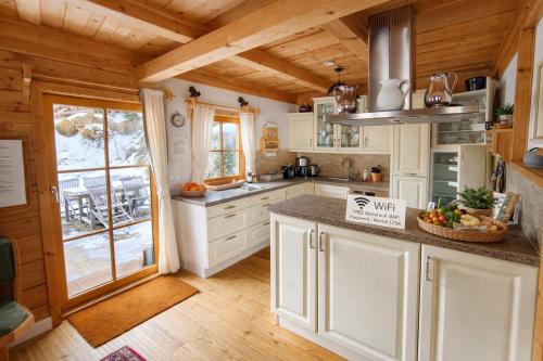 a kitchen with white cabinets and a large window at Chalet Steiermark in Pusterwald