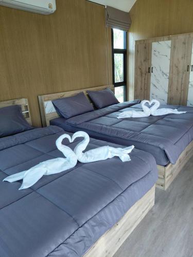 two beds with white hearts on them in a bedroom at ลึกลับรีสอร์ทบ้านนา in Nakhon Nayok