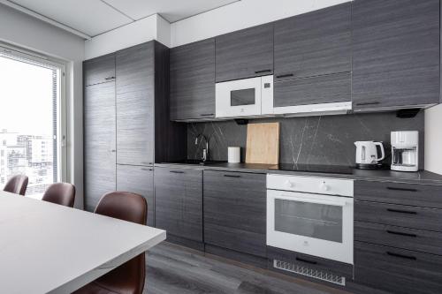 a kitchen with wooden cabinets and a table with chairs at Luxurious Penthouse - Hot Tub & Sauna in Tampere