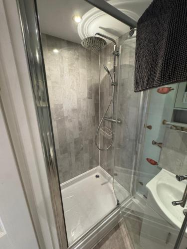 a shower with a glass door in a bathroom at Charming one bedroom cottage in Basingstoke