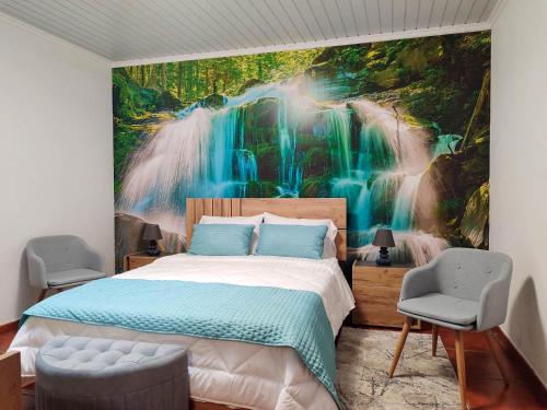 a bedroom with a waterfall mural on the wall at Paraíso Verde in Algarvia
