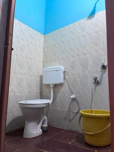 a bathroom with a toilet and a bucket at Aarvi Residency in Māvalli