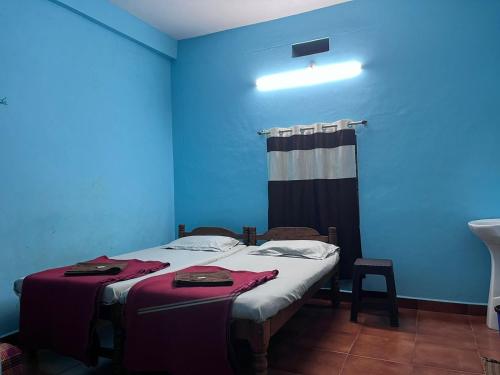 a room with two beds and a blue wall at Aarvi Residency in Māvalli