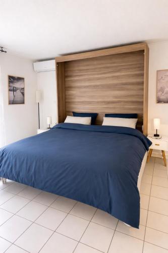 a bedroom with a blue bed with a wooden headboard at Mon Appart avec Terrasse et Piscine in Roquebrune-Cap-Martin