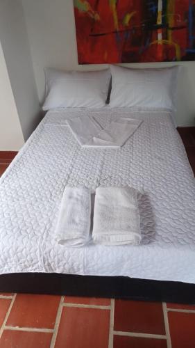 a white bed with two white pillows on it at Hacienda Torcoroma in Bucaramanga