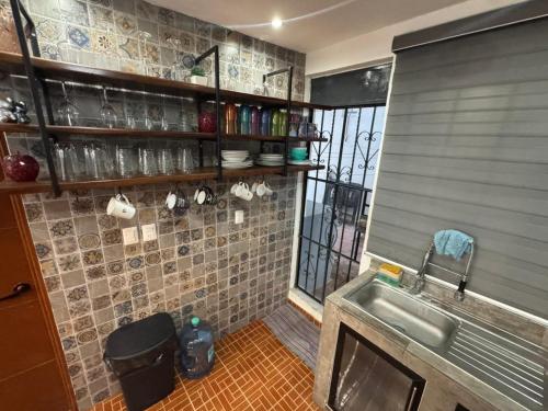 a kitchen with a sink and a tiled wall at Casa Santa Cruz in Chetumal