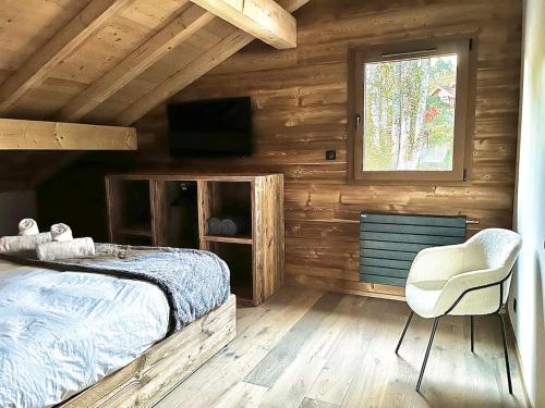 a bedroom with a bed and a chair and a window at Chalet Les Roitelets 5 étoiles avec jacuzzi sauna in Gérardmer