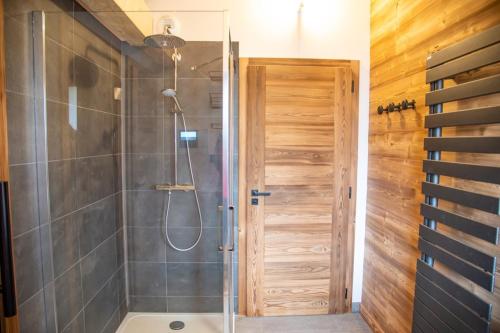 a shower with a glass door in a bathroom at Chalet Les Roitelets 5 étoiles avec jacuzzi sauna in Gérardmer