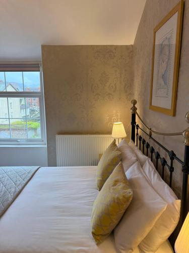 a bedroom with a bed with pillows and a window at Haversham House - Adults Only in Llandudno