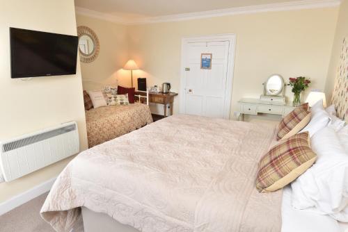a bedroom with a bed and a flat screen tv at The Royal Hotel Cromarty in Cromarty