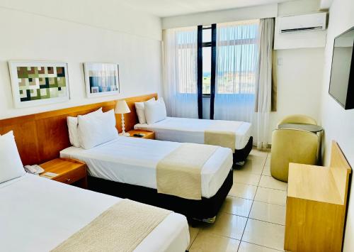 a hotel room with two beds and a television at Copacabana Mar Hotel in Rio de Janeiro