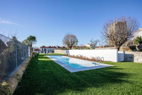 a swimming pool in a yard next to a fence at Liiiving in Porto - Haven Pool Apartment in Porto