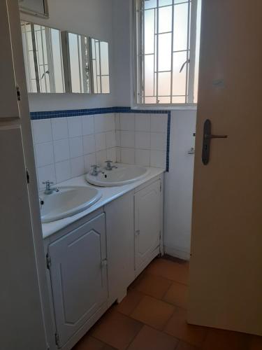 a bathroom with two sinks and two mirrors at Portia inn accommodation in Pretoria