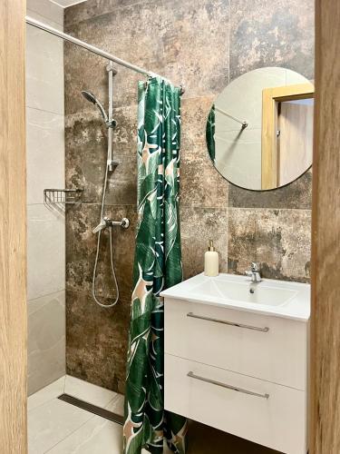a bathroom with a shower and a sink and a mirror at Mirabelka - domek in Podostrówek