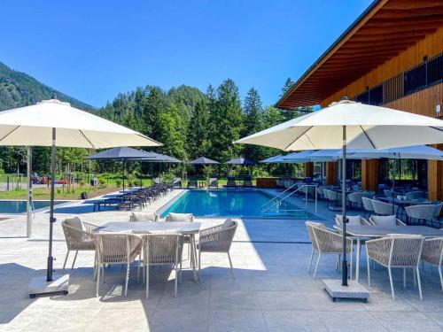 Eine Terrasse mit Tischen und Sonnenschirmen neben einem Pool in der Unterkunft Campingresort Hinterstoder in Hinterstoder