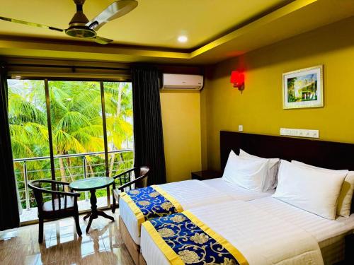 a bedroom with a bed and a table and a window at Blue Wave Guesthouse Maldives - Book FB a week gets a free excursion in Kudahuvadhoo