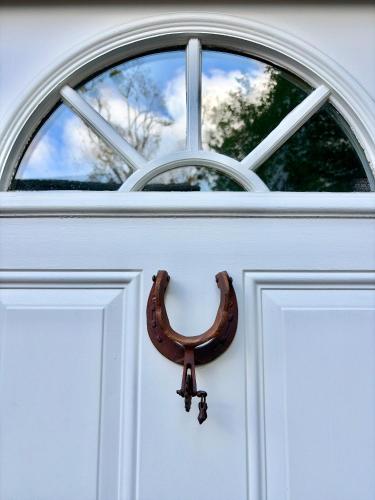 a horseshoe on a white door with a window at Morse Cottage in Houston