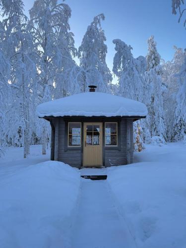 a small shed covered in snow with trees in the background at Pusikko - Cozy Lake Villa - Ice Swimming - Sauna - Fireplace - Barbeque Shed in Kuusamo