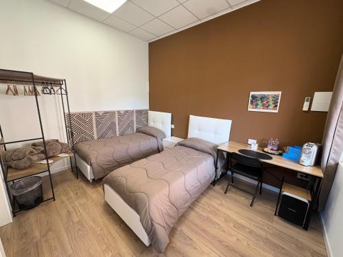 a room with two beds and a desk and a table at Elco Rooms Malpensa in Lonate Pozzolo